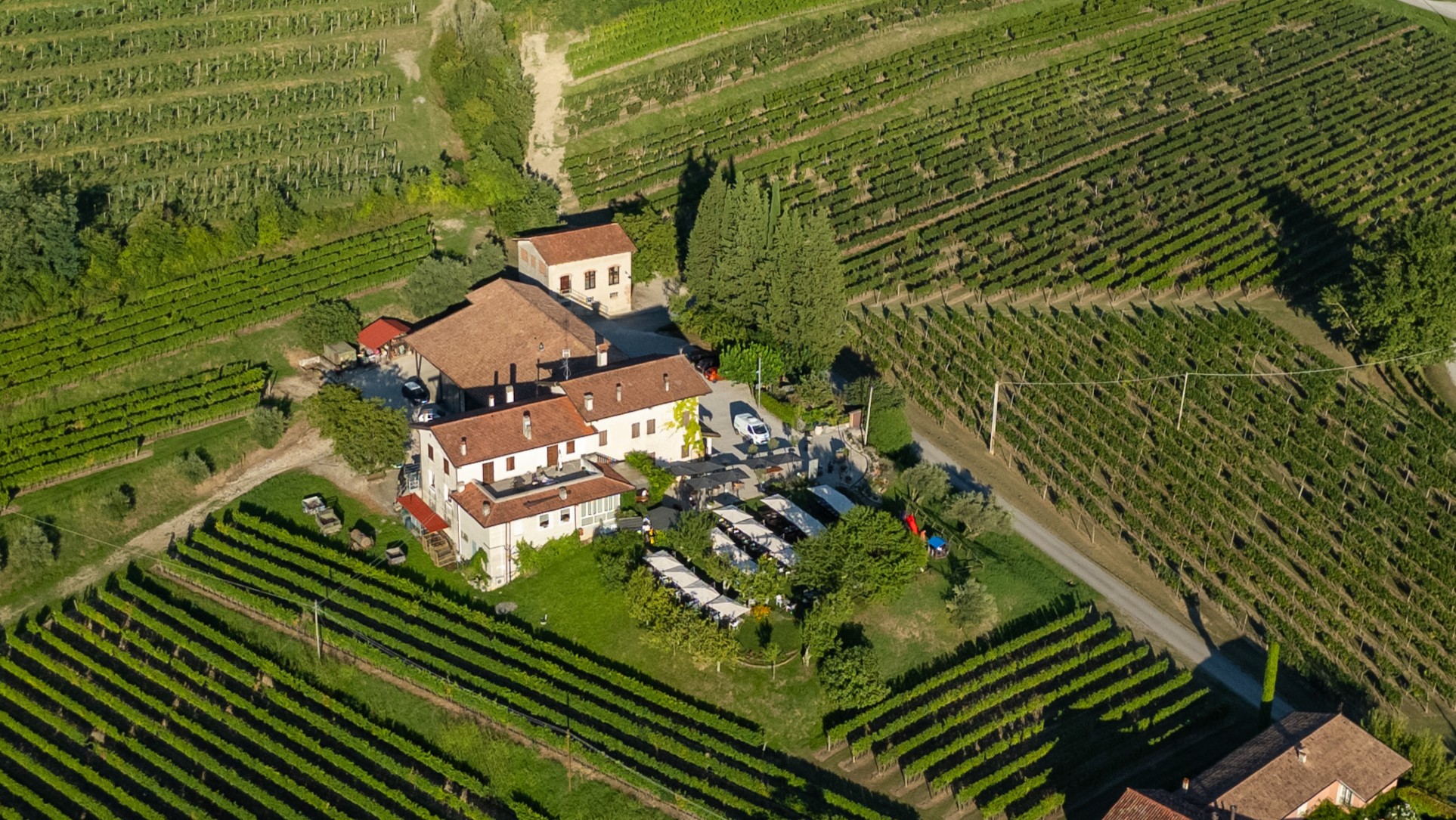 L’interno accogliente dell’Osteria Solder: un bancone moderno in acciaio con vini e distillati, un grande barile in legno decorativo, soffitto con travi a vista e sale apparecchiate con eleganza semplice e autentica.